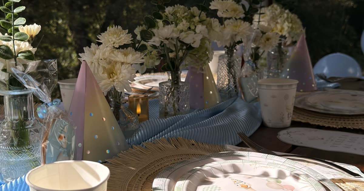 ETERIA outdoor celebration table styled with blue textiles, ivory flowers, and layered place settings